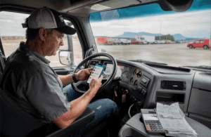 Owner-operator reviewing dispatch messages on a smartphone inside a truck cab