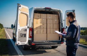 Sprinter van loaded with boxes while a driver checks a shipment list on the roadside